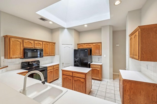 kitchen featuring sink, light tile patterned floors, backsplash, a center island, and black appliances