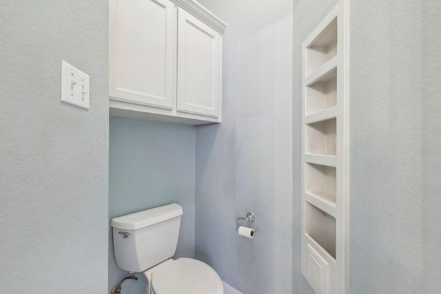 bathroom featuring built in shelves and toilet