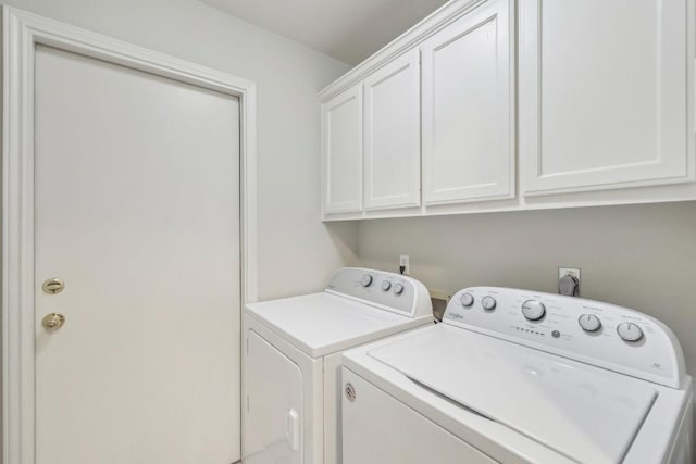 clothes washing area with cabinets and washer and dryer