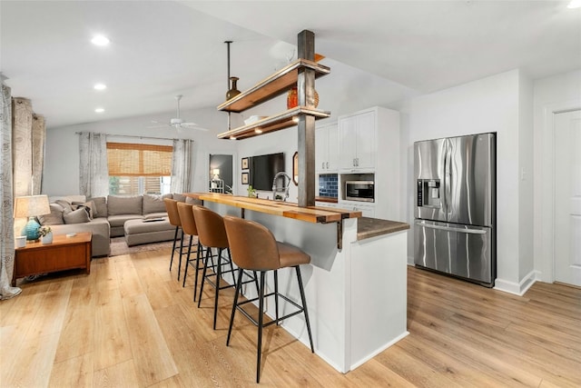 kitchen featuring wood counters, a breakfast bar area, white cabinetry, stainless steel appliances, and light hardwood / wood-style floors