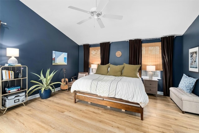 bedroom with ceiling fan, vaulted ceiling, multiple windows, and light wood-type flooring