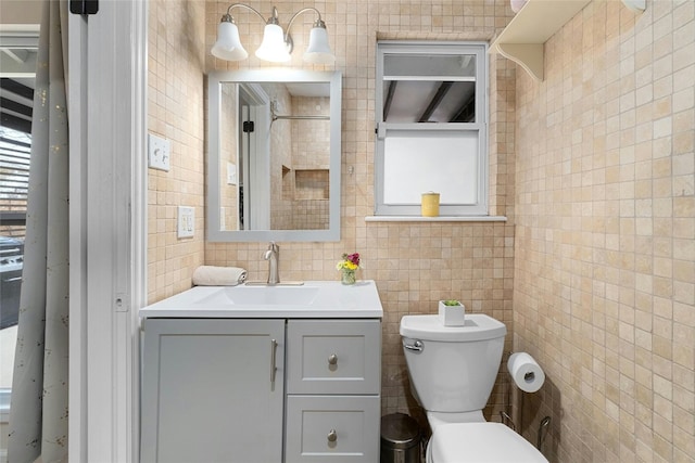 bathroom featuring tile walls, vanity, and toilet