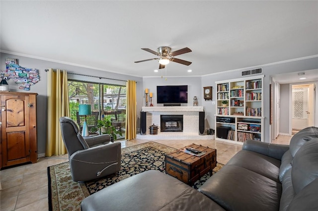 living room featuring ornamental molding, light tile patterned floors, ceiling fan, and a fireplace