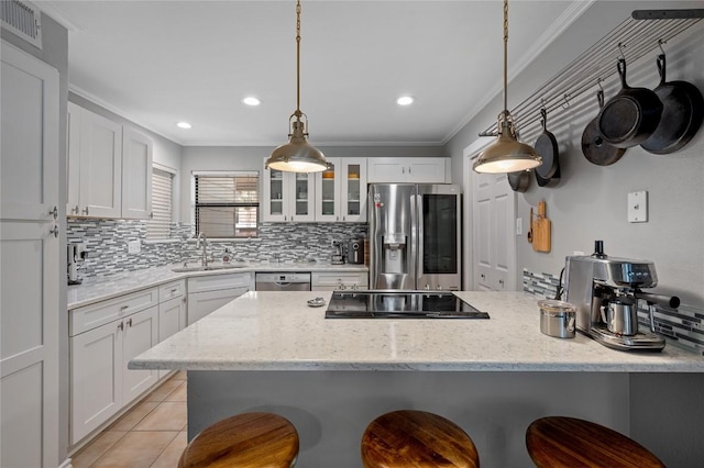 kitchen featuring appliances with stainless steel finishes, sink, white cabinets, a kitchen breakfast bar, and light stone counters