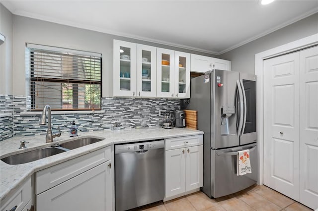 kitchen with appliances with stainless steel finishes, sink, white cabinets, crown molding, and light stone countertops