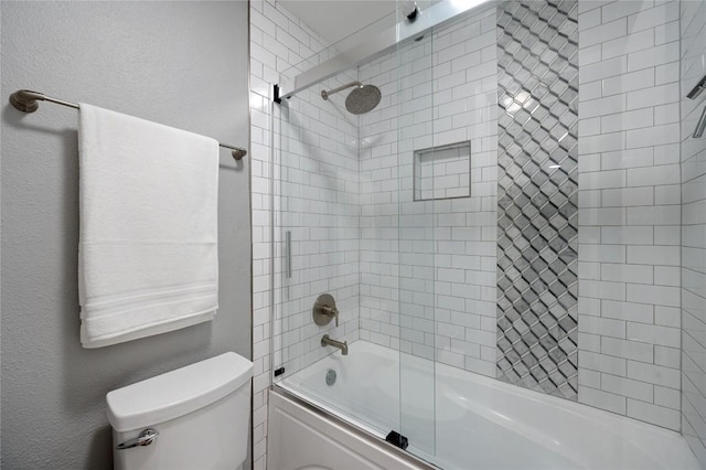 bathroom with toilet and combined bath / shower with glass door