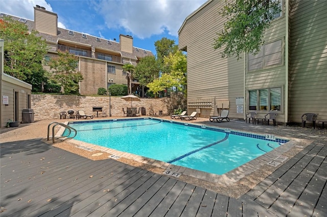 view of pool with a wooden deck and a patio