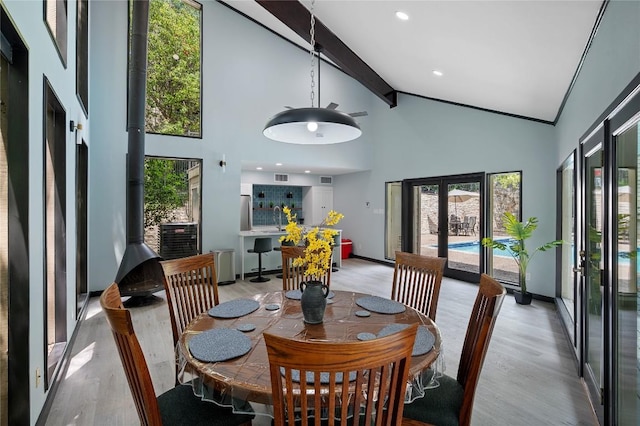 dining area with high vaulted ceiling, light hardwood / wood-style flooring, beam ceiling, and french doors