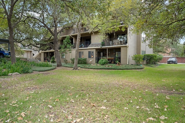 back of house with a yard and a balcony