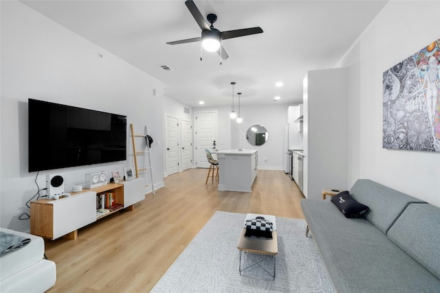 living room featuring ceiling fan and light hardwood / wood-style flooring