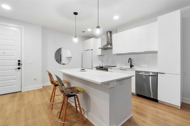 kitchen with sink, white cabinets, wall chimney exhaust hood, and appliances with stainless steel finishes