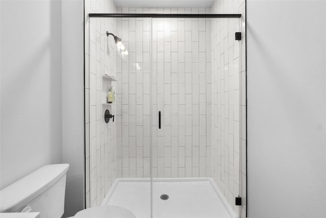 bathroom featuring toilet and a shower with shower door