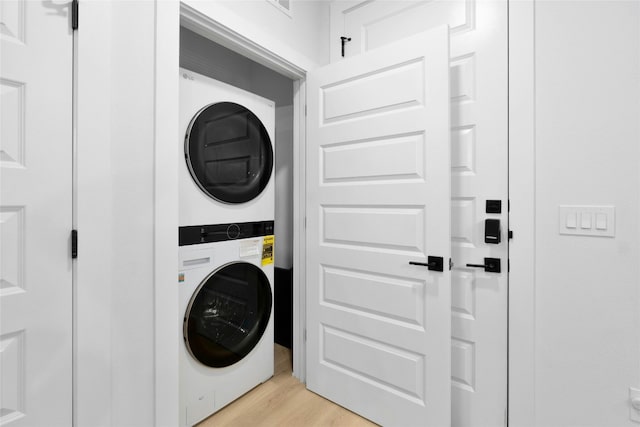 laundry room with stacked washer and dryer and light hardwood / wood-style flooring