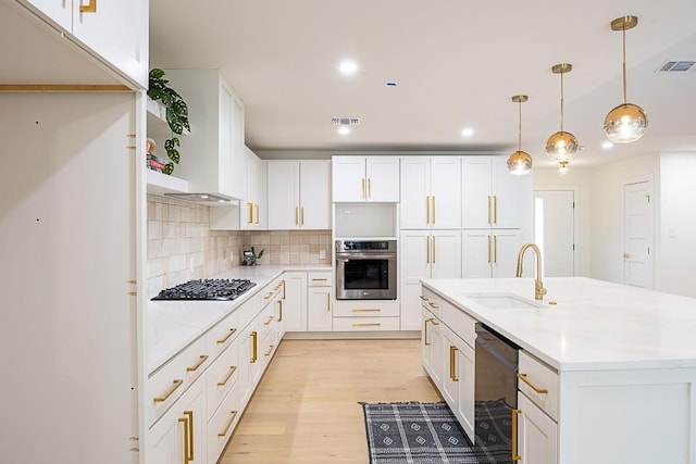 kitchen with pendant lighting, appliances with stainless steel finishes, sink, and white cabinets