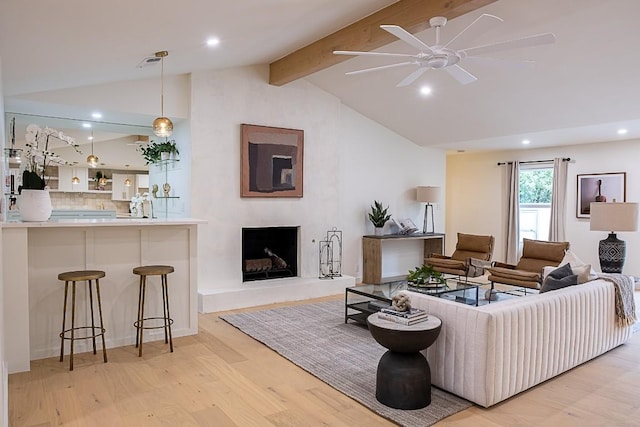 living room with lofted ceiling with beams, ceiling fan, and light wood-type flooring