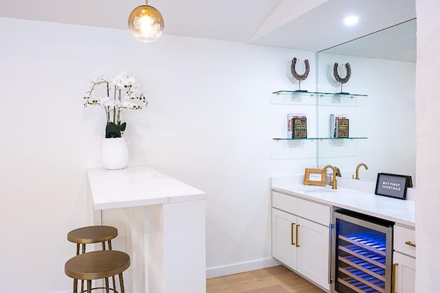 bar featuring wine cooler, sink, pendant lighting, light hardwood / wood-style floors, and white cabinets