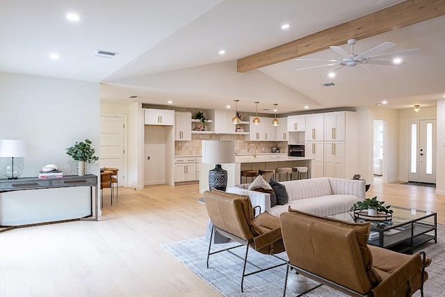 living room featuring sink, lofted ceiling with beams, ceiling fan, and light wood-type flooring