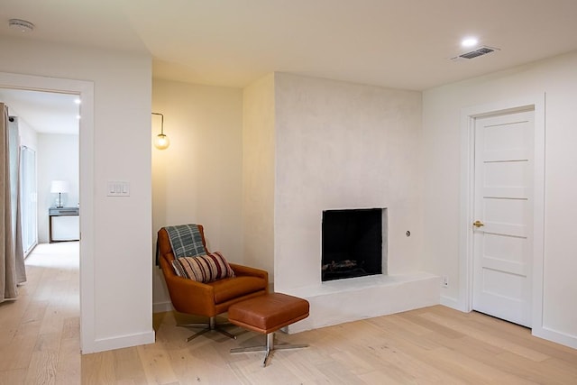 living area featuring a large fireplace and light wood-type flooring