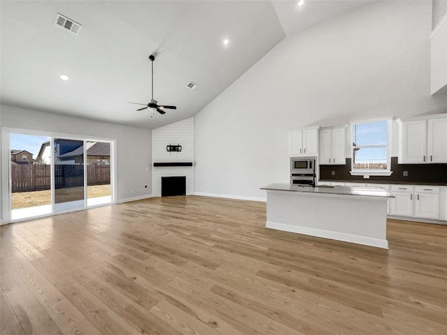 17401 Howdy Way, Manor, TX 78653 - kitchen with appliances with stainless steel finishes, high vaulted ceiling, ceiling fan, white cabinetry, and a kitchen island with sink