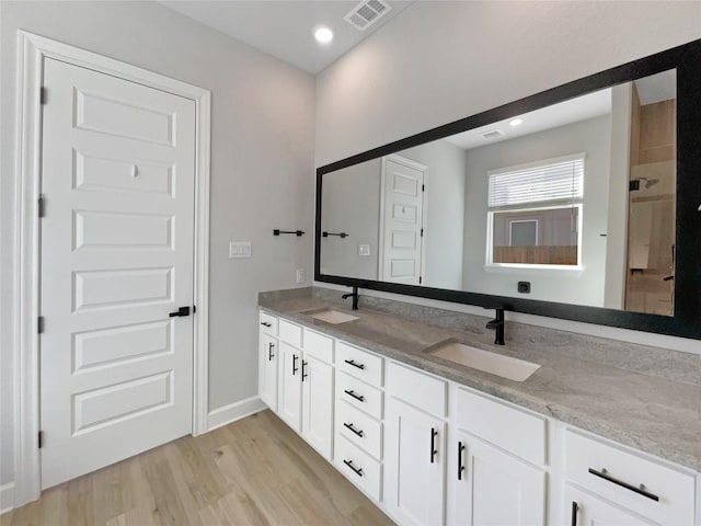17401 Howdy Way, Manor, TX 78653 - bathroom with double vanity, wood finished floors, a tile shower, recessed lighting, and baseboards