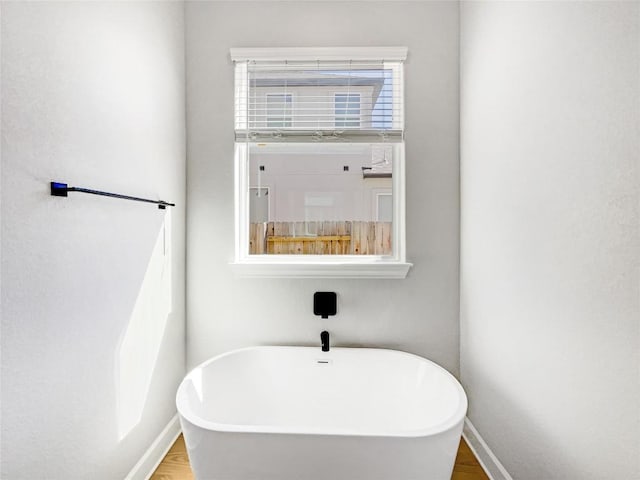 17401 Howdy Way, Manor, TX 78653 - full bathroom featuring a soaking tub, wood finished floors, and baseboards
