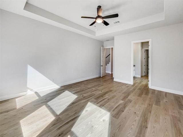 17401 Howdy Way, Manor, TX 78653 - unfurnished bedroom featuring a raised ceiling, baseboards, light wood-style floors, and a ceiling fan