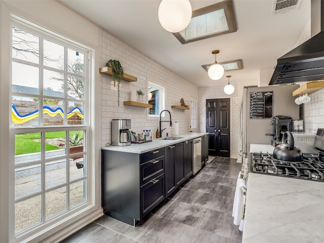 kitchen with pendant lighting, sink, light stone counters, extractor fan, and tasteful backsplash