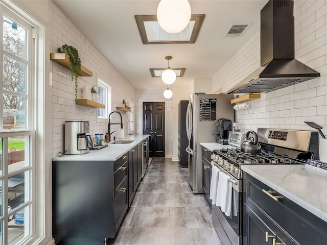 kitchen featuring sink, stainless steel appliances, light stone counters, ventilation hood, and decorative light fixtures