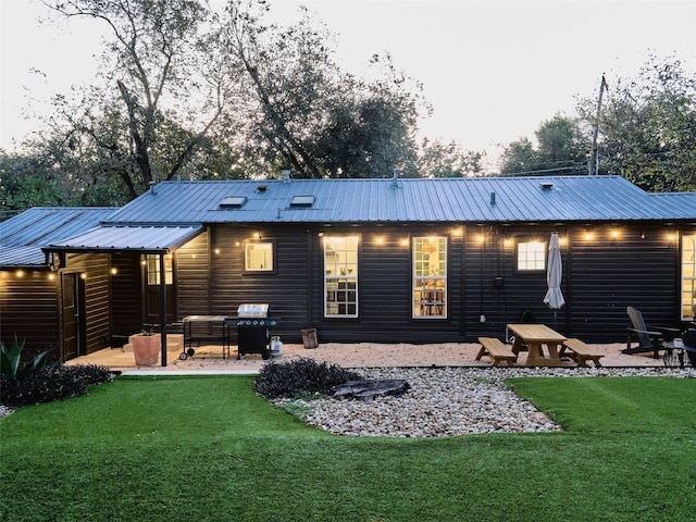 back house at dusk with a patio and a yard