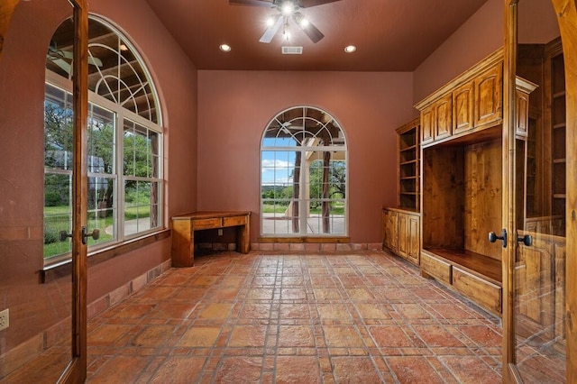 mudroom featuring plenty of natural light, built in desk, and ceiling fan