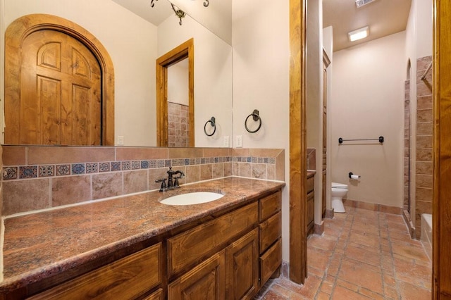 bathroom featuring tasteful backsplash, vanity, and toilet