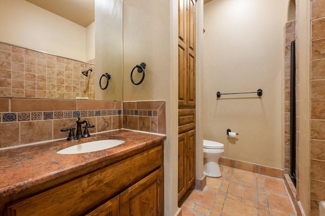 bathroom with tasteful backsplash, vanity, toilet, and a shower with door