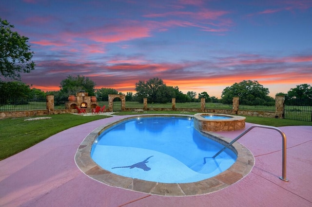 pool at dusk with a patio area, a lawn, an outdoor fireplace, and an in ground hot tub