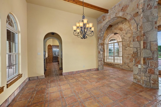 unfurnished dining area with beam ceiling, a high ceiling, and a notable chandelier