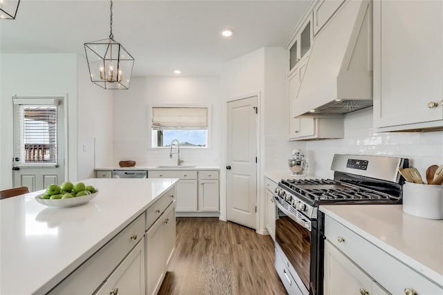 kitchen with pendant lighting, sink, appliances with stainless steel finishes, white cabinetry, and custom exhaust hood