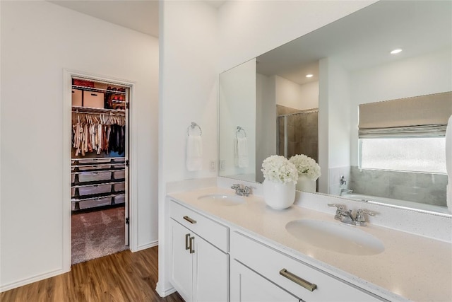 bathroom featuring hardwood / wood-style flooring, plus walk in shower, and vanity