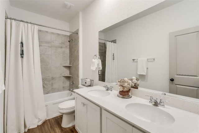 full bathroom with wood-type flooring, vanity, shower / tub combo, and toilet