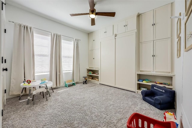 recreation room with ceiling fan and light carpet