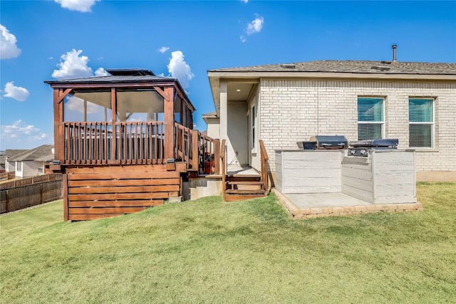 rear view of property with a gazebo, a yard, exterior kitchen, and a deck