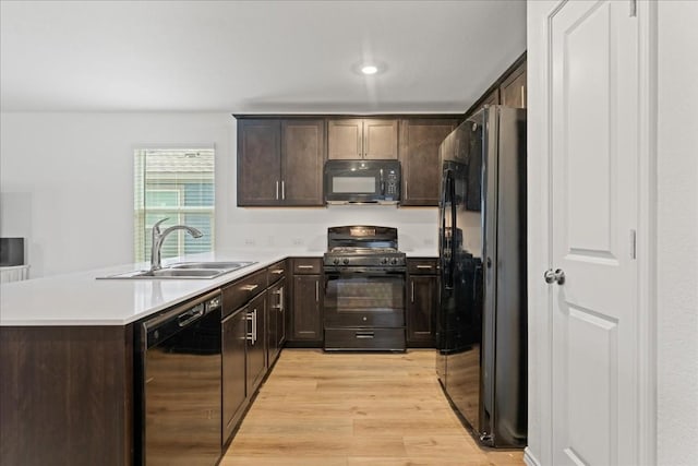 kitchen featuring sink, dark brown cabinets, light wood-type flooring, kitchen peninsula, and black appliances