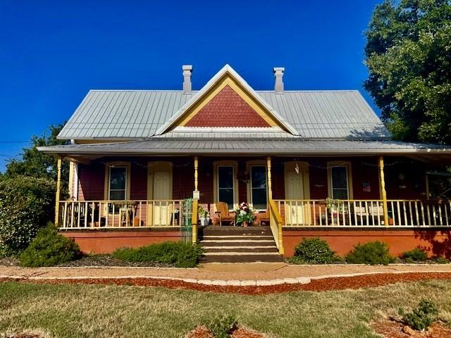 1307 Wright St, Llano, TX 78643 - view of front of house featuring covered porch, a chimney, and metal roof