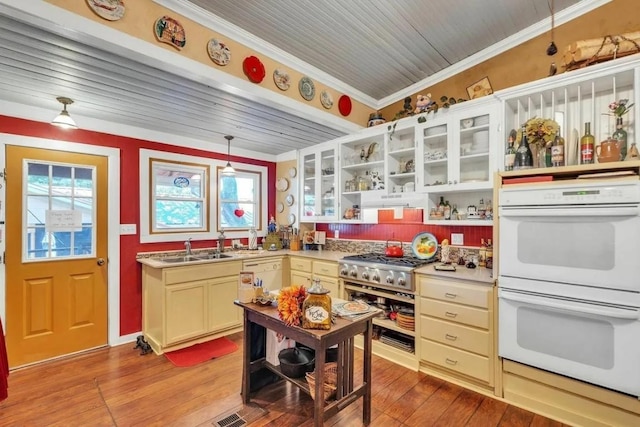 kitchen with sink, crown molding, light hardwood / wood-style flooring, double oven, and decorative light fixtures