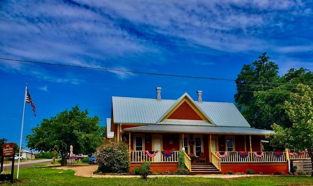 1307 Wright St, Llano, TX 78643 - view of front of home featuring covered porch, a chimney, metal roof, and a front yard