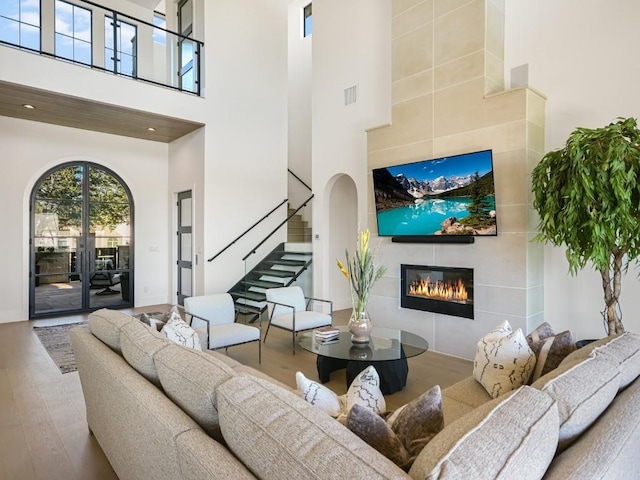 living room with hardwood / wood-style floors, a fireplace, and a high ceiling