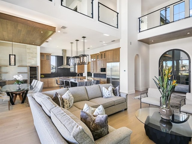 living room with sink, a high ceiling, and light wood-type flooring