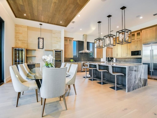 dining area featuring wood ceiling, light wood-type flooring, sink, and wine cooler