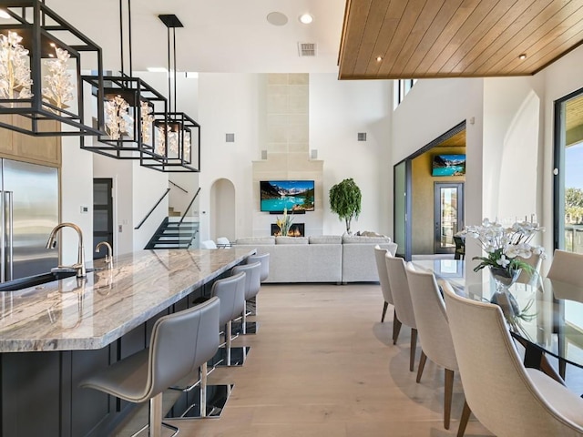 kitchen with sink, built in refrigerator, hanging light fixtures, light stone countertops, and wooden ceiling