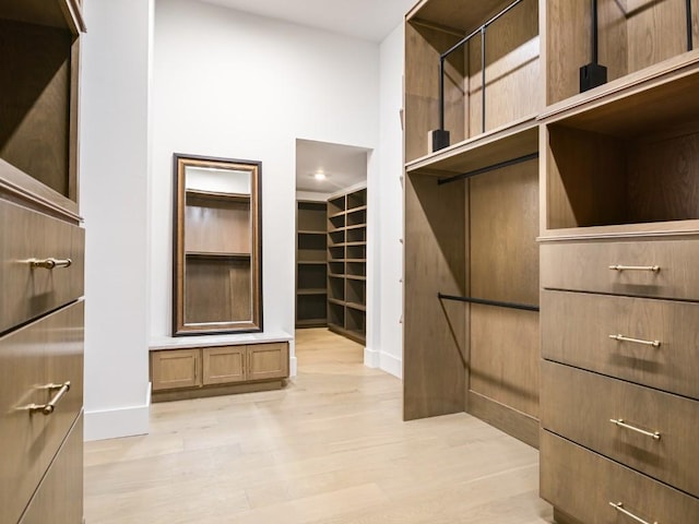 spacious closet featuring light hardwood / wood-style floors and a high ceiling