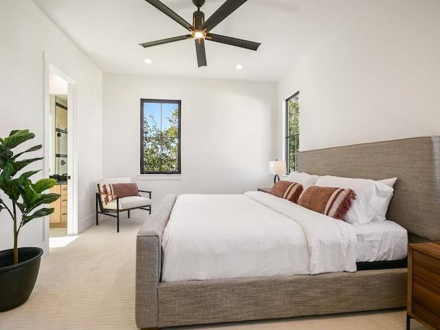 carpeted bedroom featuring ceiling fan, ensuite bath, and multiple windows