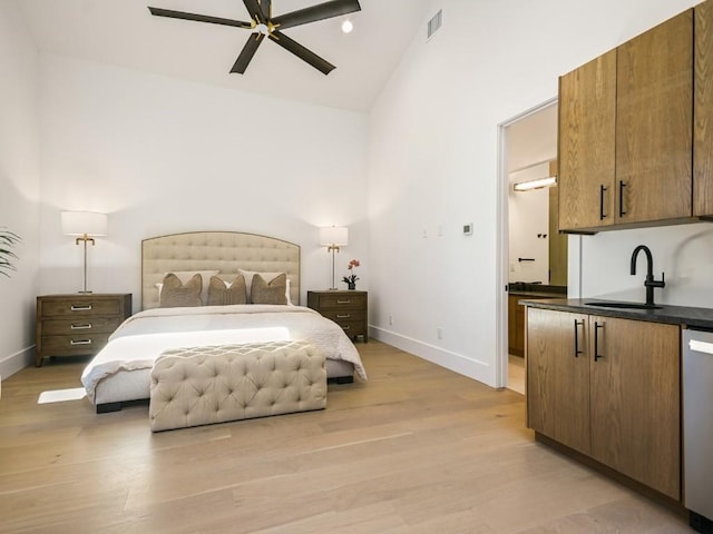 bedroom featuring high vaulted ceiling, sink, and light wood-type flooring